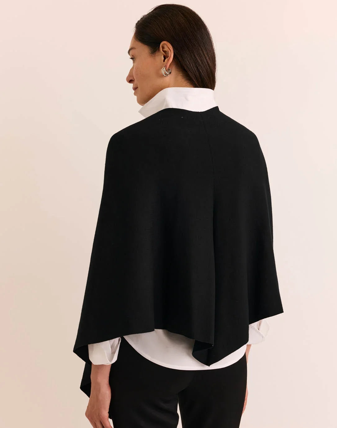 A woman modeling a black wrap shawl by The H Edition Mabel Tab Fringe Wrap