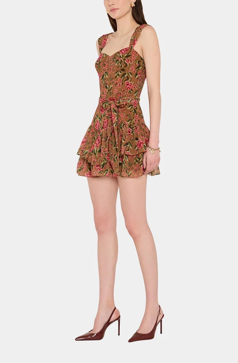 A model wearing a sleeveless ruffled mini dress with a brown, pink, and green floral pattern Amanda Uprichard Kendra Skort Romper Evening Rose