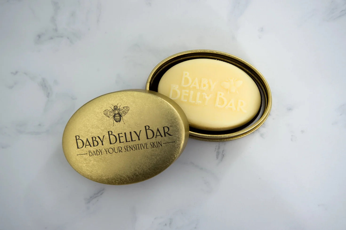 Baby Belly Bar soap in a brass container on a marble surface