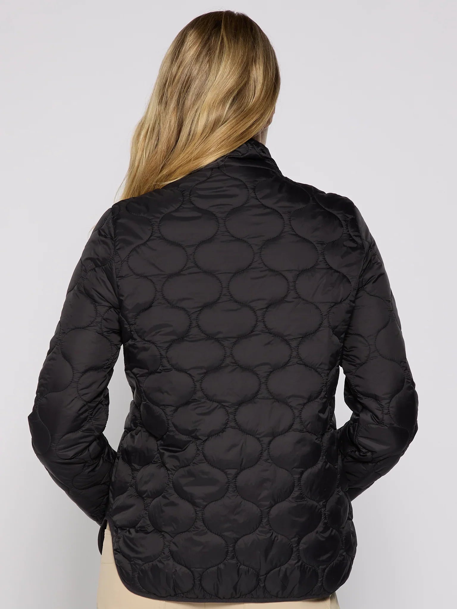Black quilted jacket worn by a person on a light gray background