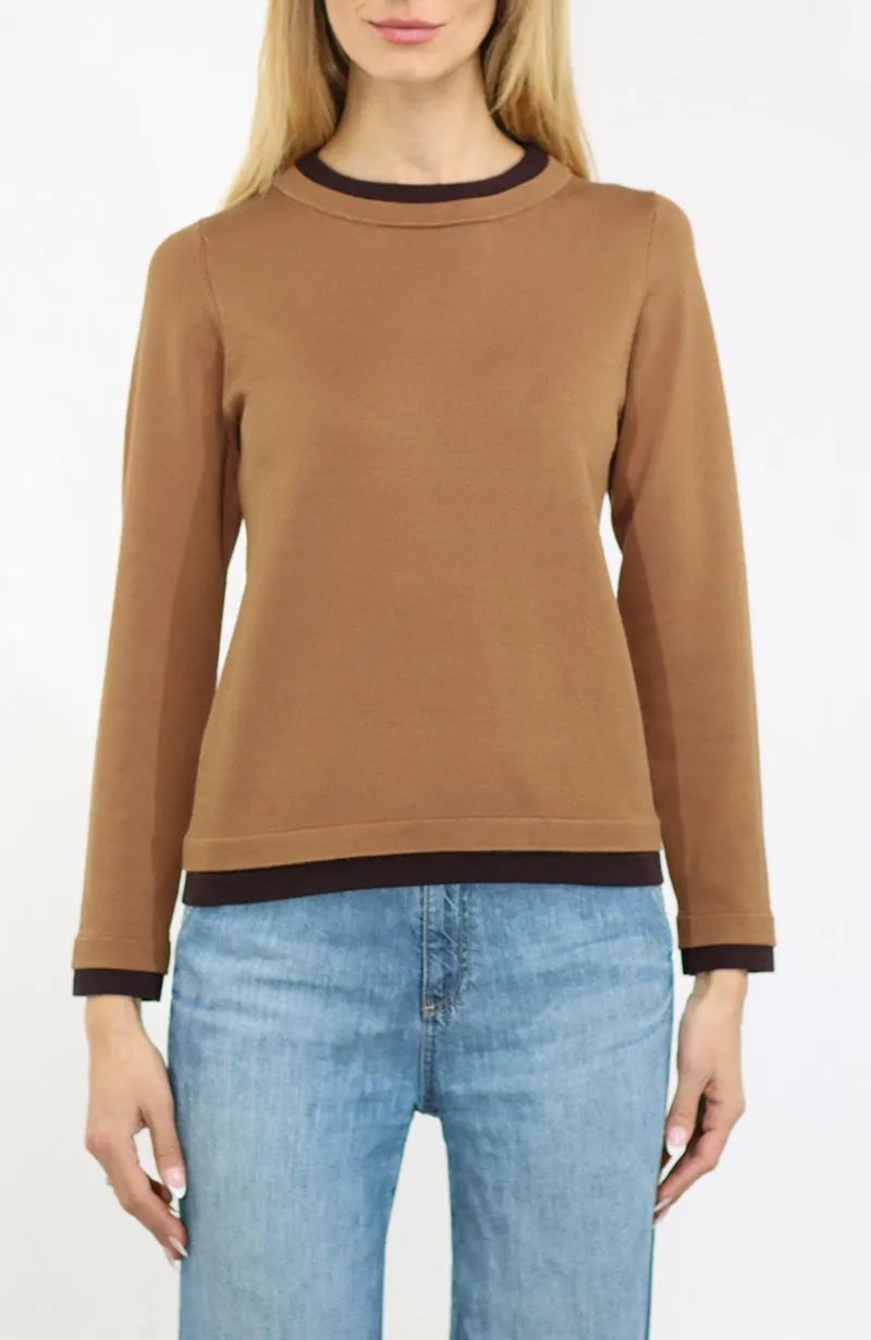 A woman wearing a brown long-sleeve crewneck sweater with dark brown ribbed trim at the collar, cuffs, and hem