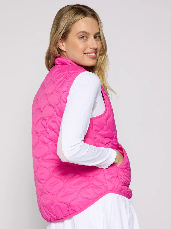 Woman wearing a pink quilted vest against a plain background
