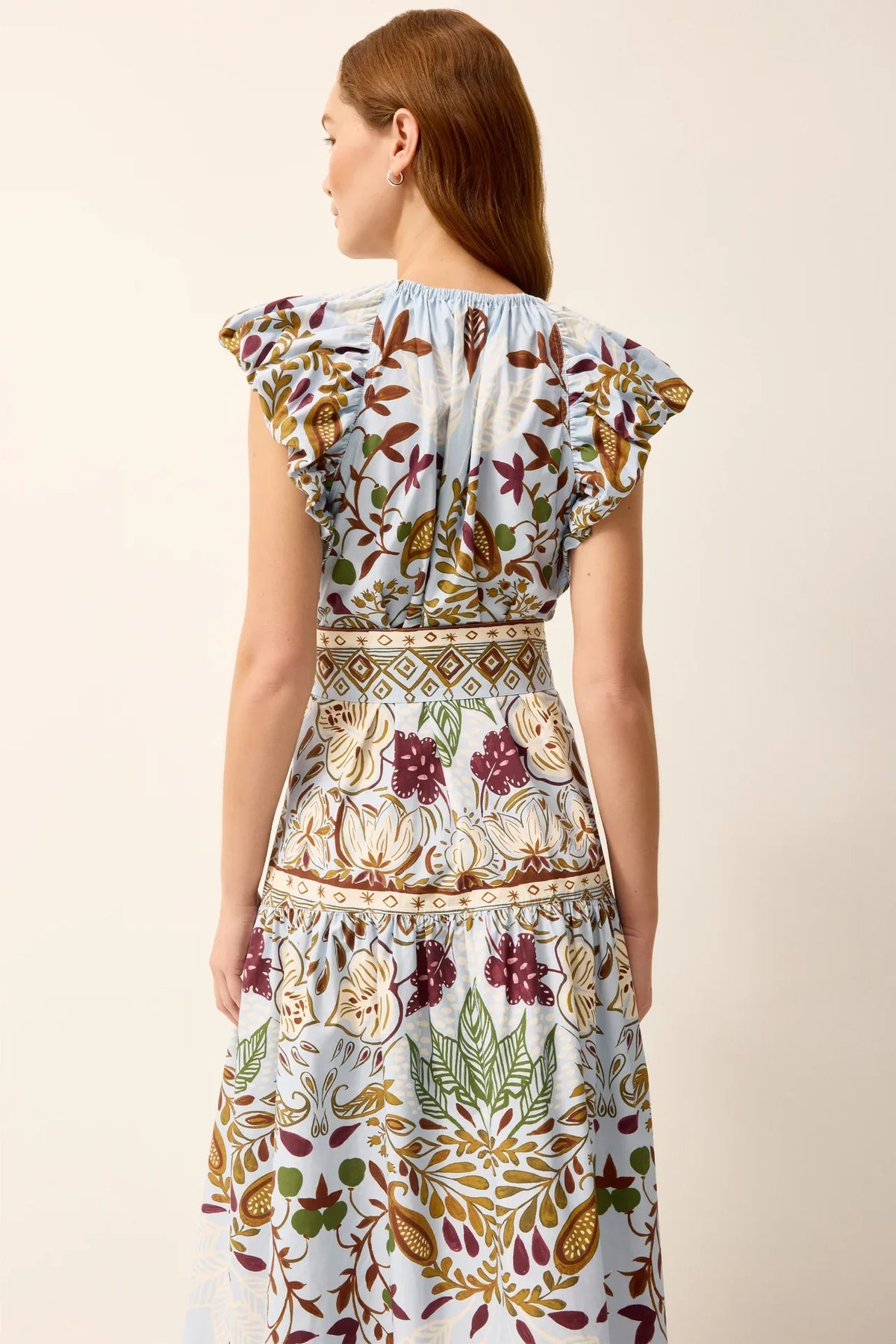 Marie Oliver Leena Dress in lush green fabric with a flowing silhouette, showcased on a mannequin with leafy background.