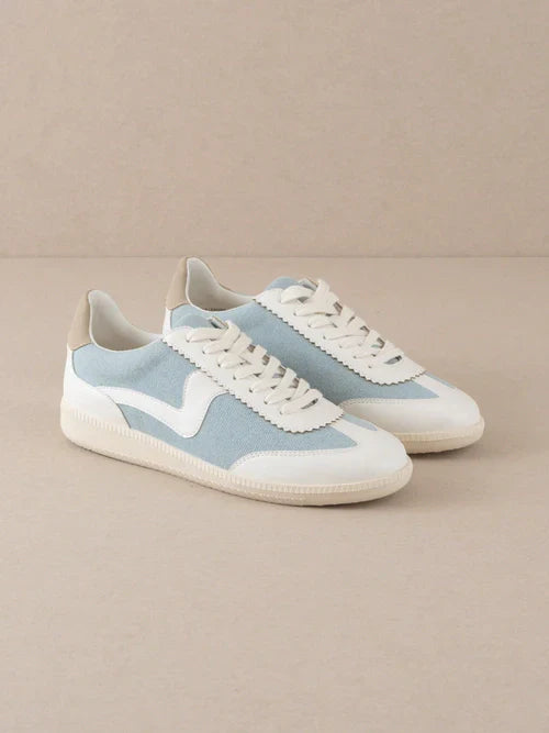 Pair of light blue and white sneakers on a beige background
