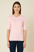 Woman wearing a light pink sweater against a beige background