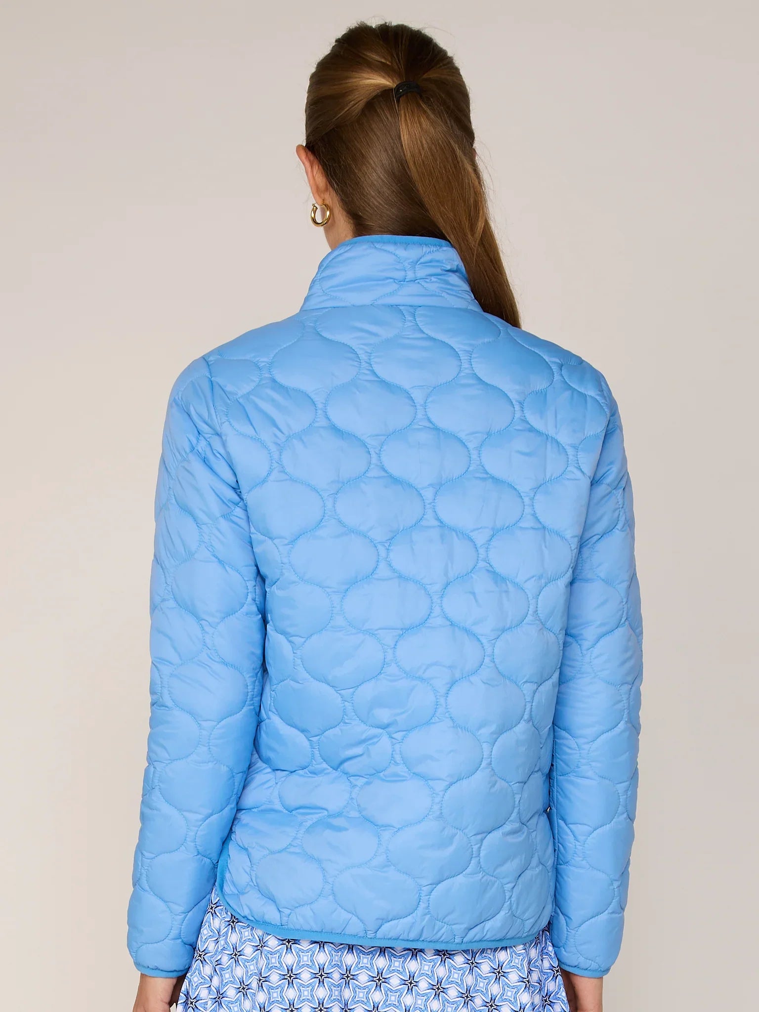 Light blue quilted jacket worn by a person on a plain background