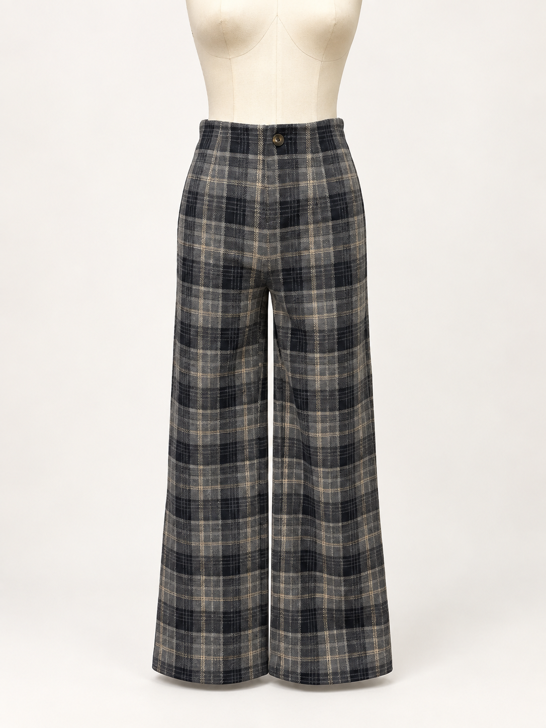 A pair of wide-leg plaid trousers displayed on a cream mannequin torso against a plain light background. The pants feature a high waist and a classic plaid pattern in dark gray, black, and beige.