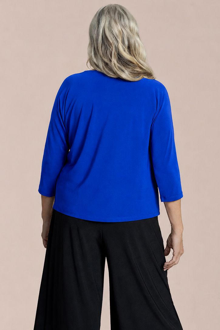 A woman modeling a bright blue V-neck top with three-quarter sleeves and a black geometric patterned accent pocket by Sympli Revel Top in Lapis