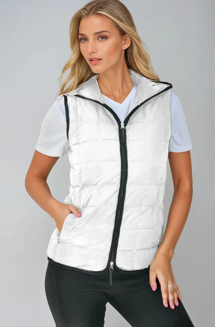 Woman wearing a white puffer vest with a black zipper on a gray background