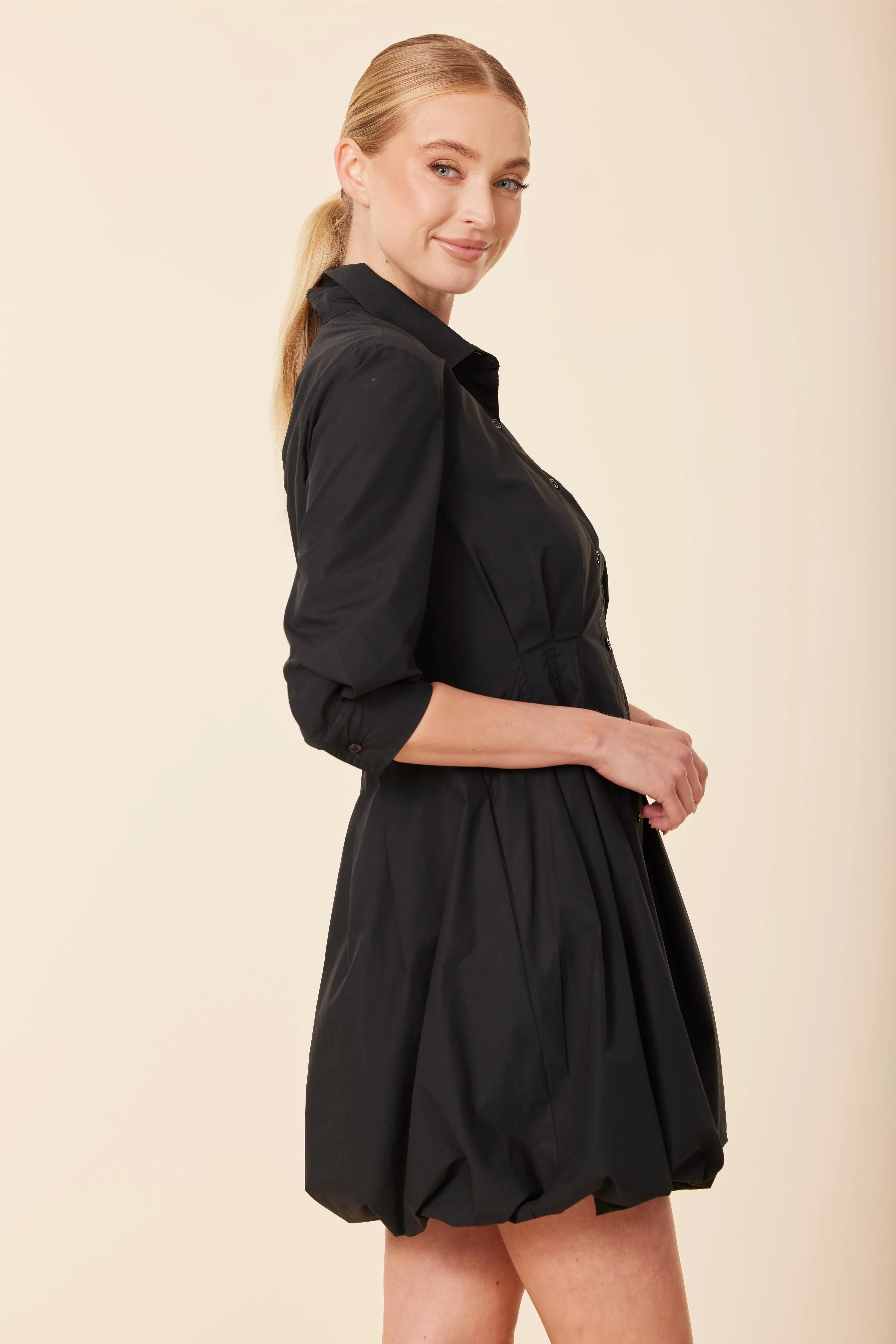 Woman wearing a black dress against a beige background