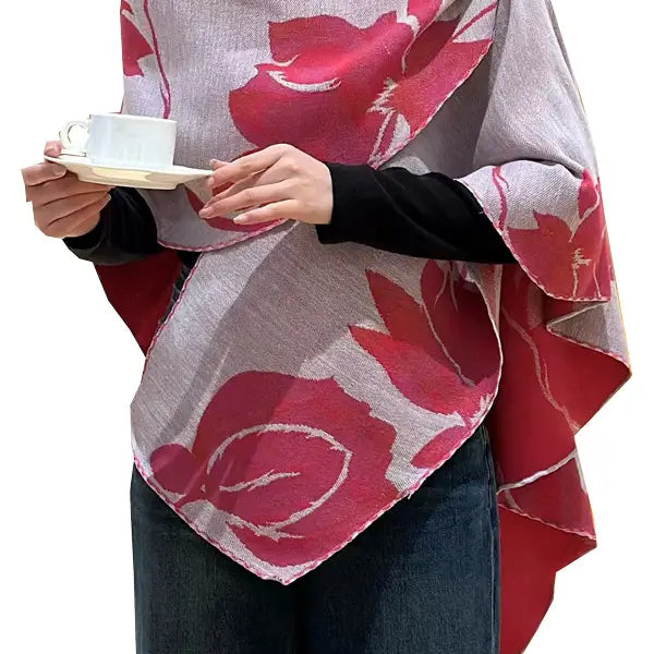 Person wearing a floral patterned shawl holding a teacup on a white background