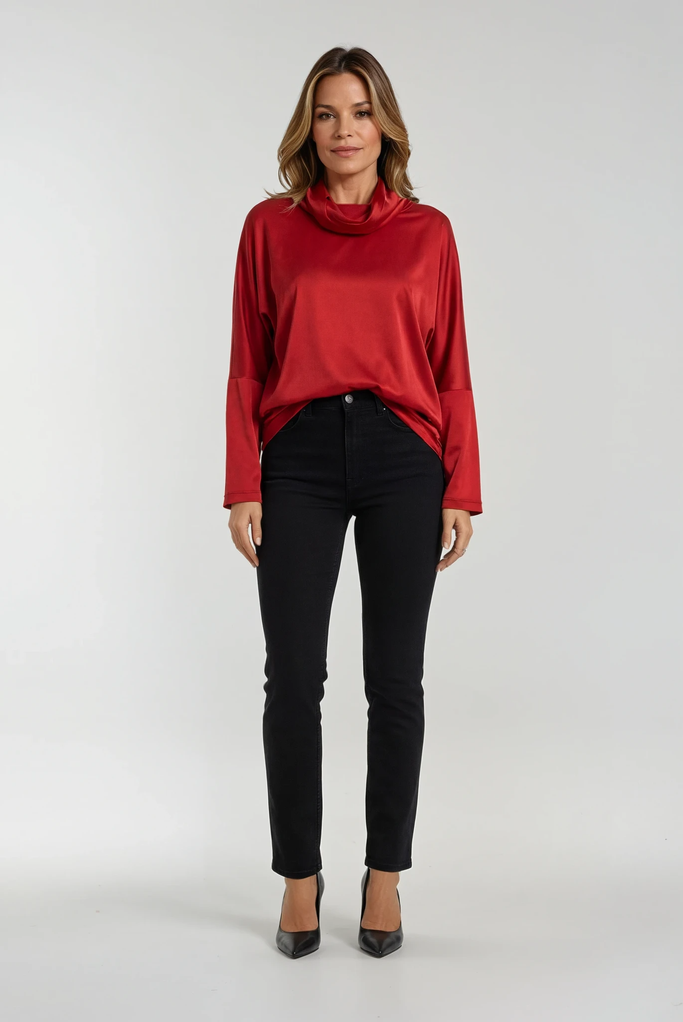 Woman wearing a red cowl-neck top and black pants on a white background