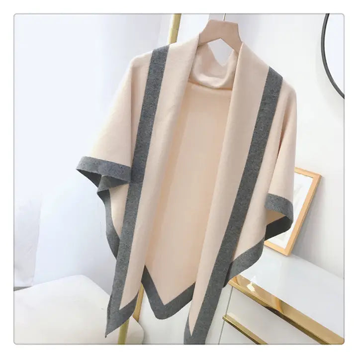 Beige poncho with gray trim on a hanger against a white background