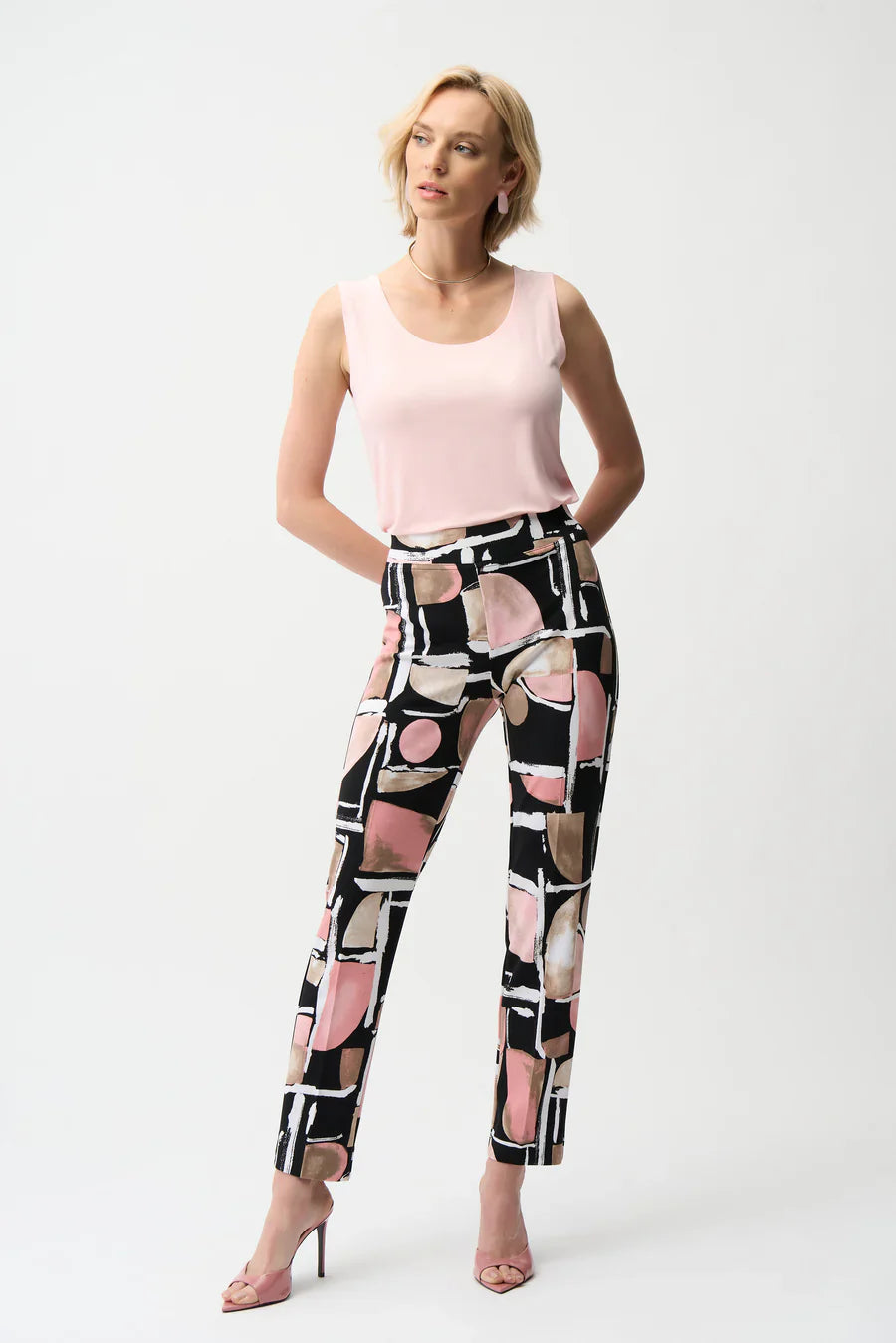 Woman wearing a pink sleeveless top and patterned pants on a white background