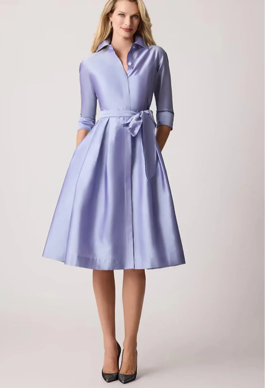 Woman wearing a light blue dress with a belt on a white background