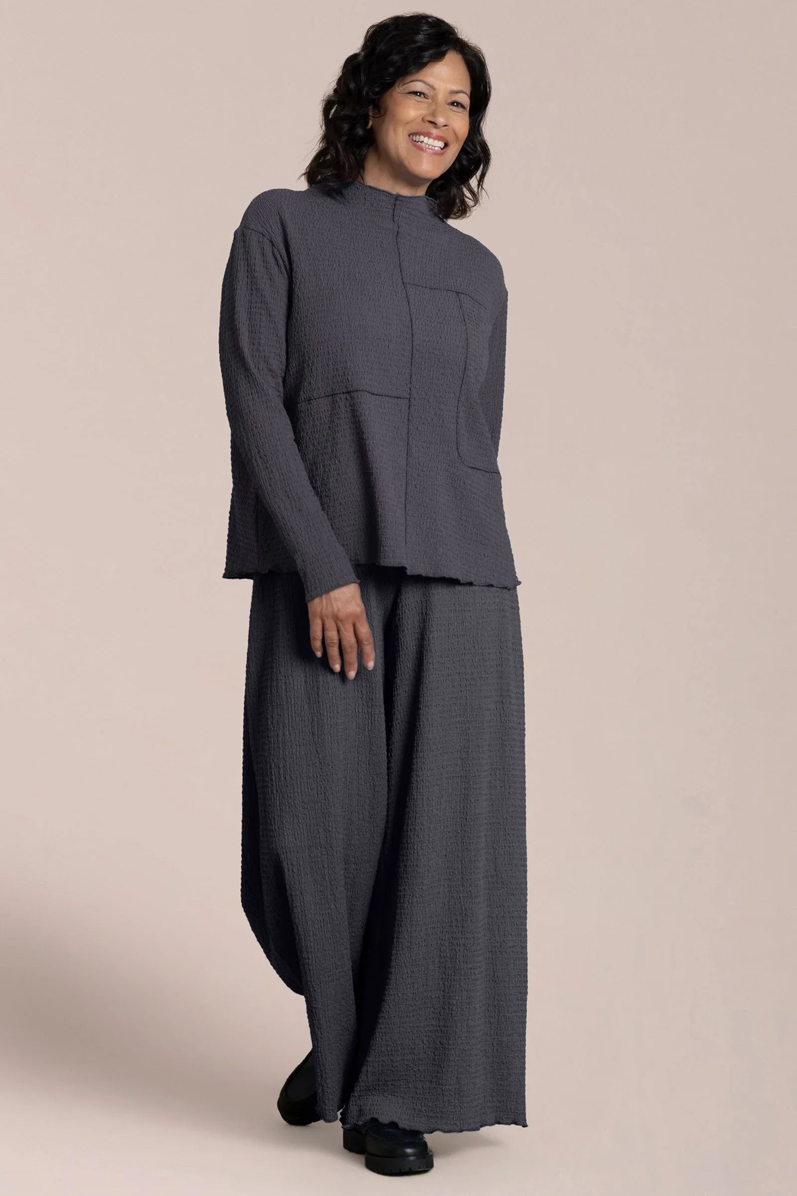 Woman wearing a gray outfit on a beige background