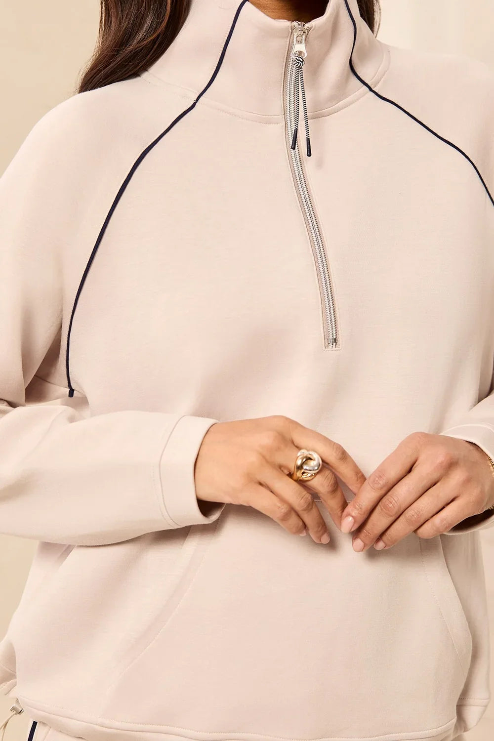 A woman modeling a matching beige tracksuit with a half-zip pullover and straight-leg pants, featuring thin black side stripes by tribal TECHNO LUX Pop Over Quarter Zip Pullover