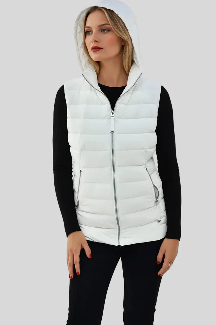 Woman wearing a white puffer vest over a black outfit on a light gray background