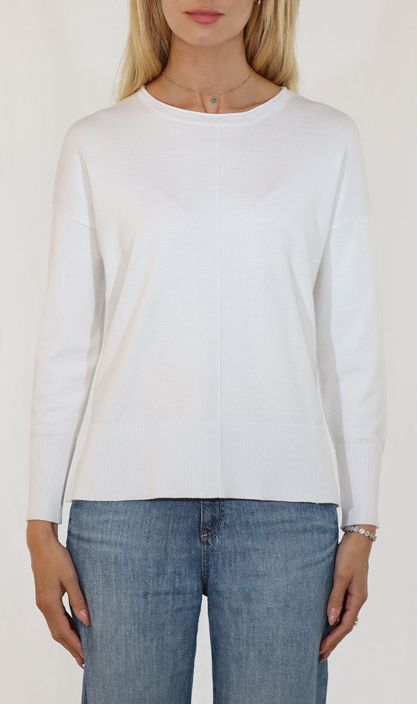 Person wearing a white long-sleeve top and blue jeans on a plain background