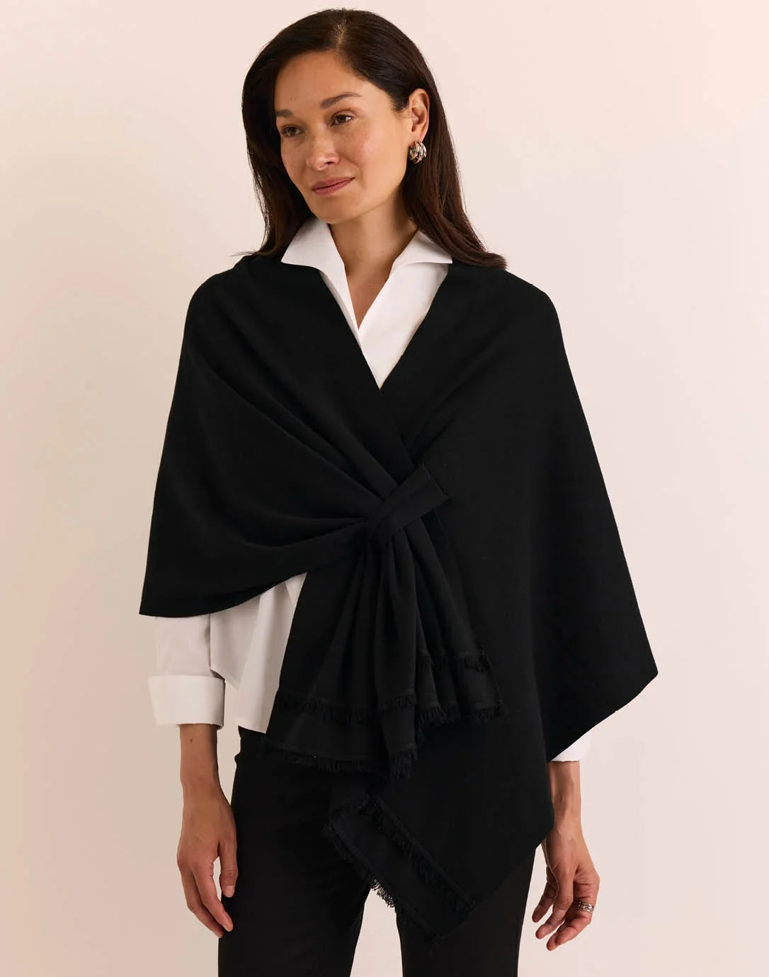 A woman modeling a black wrap shawl by  The H Edition Mabel Tab Fringe Wrap