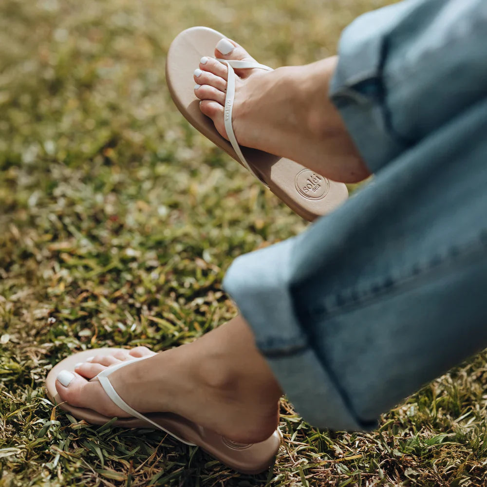 Person wearing white sandals on grass