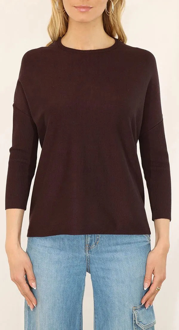 Woman wearing a dark brown sweater and blue jeans on a white background