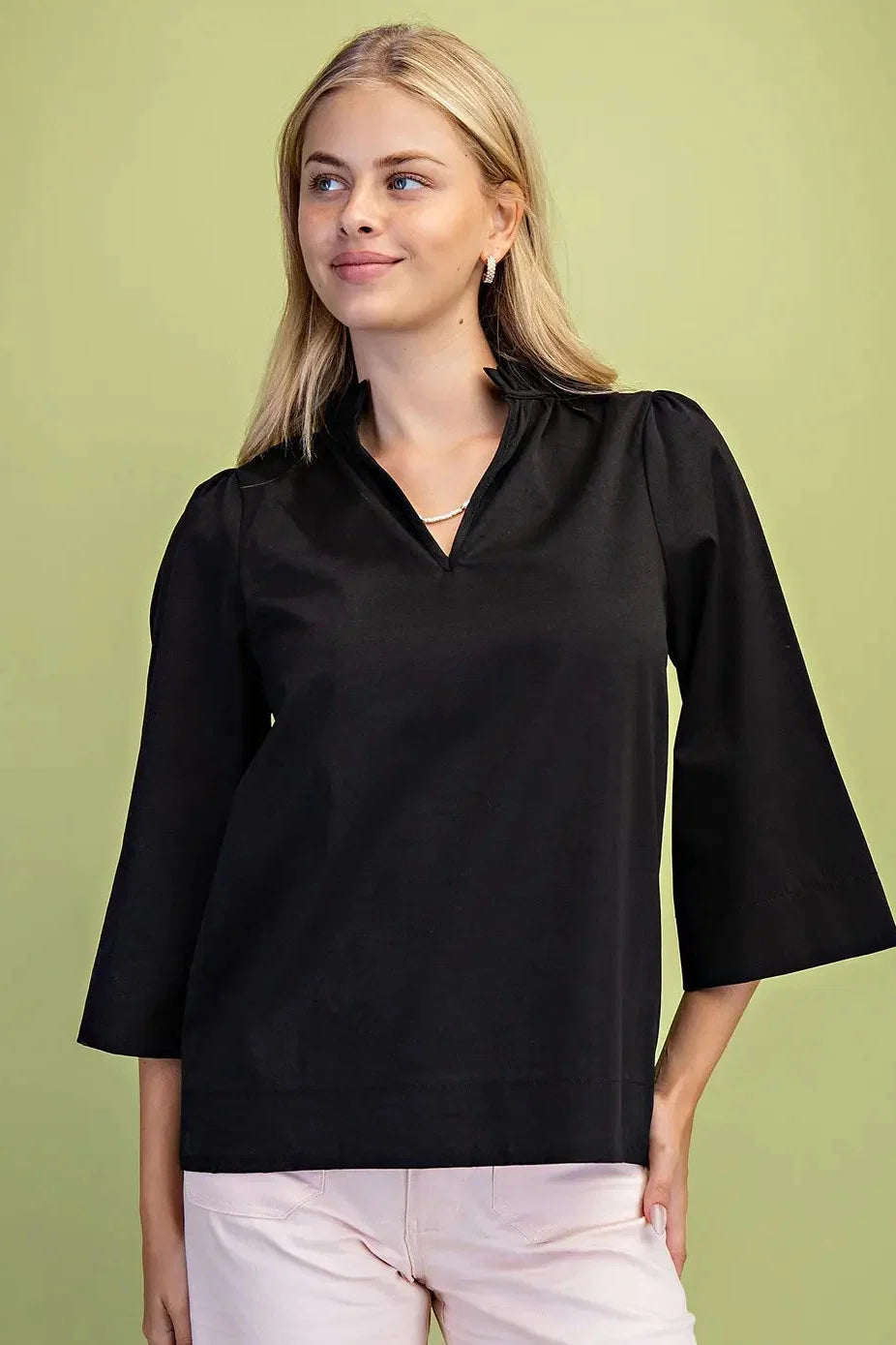 A woman modeling a black three-quarter sleeve top with a V-neckline Black Ruffled Neck Blouse