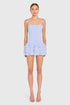Woman wearing a light blue strapless dress with ruffled layers on a white background