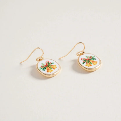 Gold earrings with circular designs featuring colorful Christmas bells bows on a light gray background