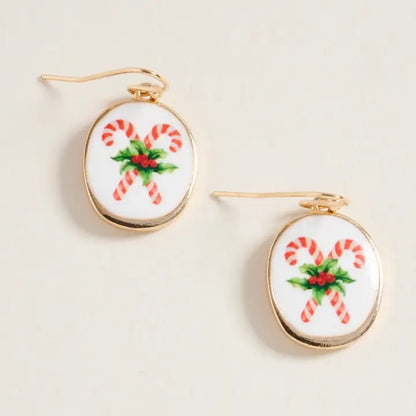 Pair of earrings with candy cane and holly design on a beige background