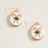 Pair of earrings with candy cane and holly design on a beige background