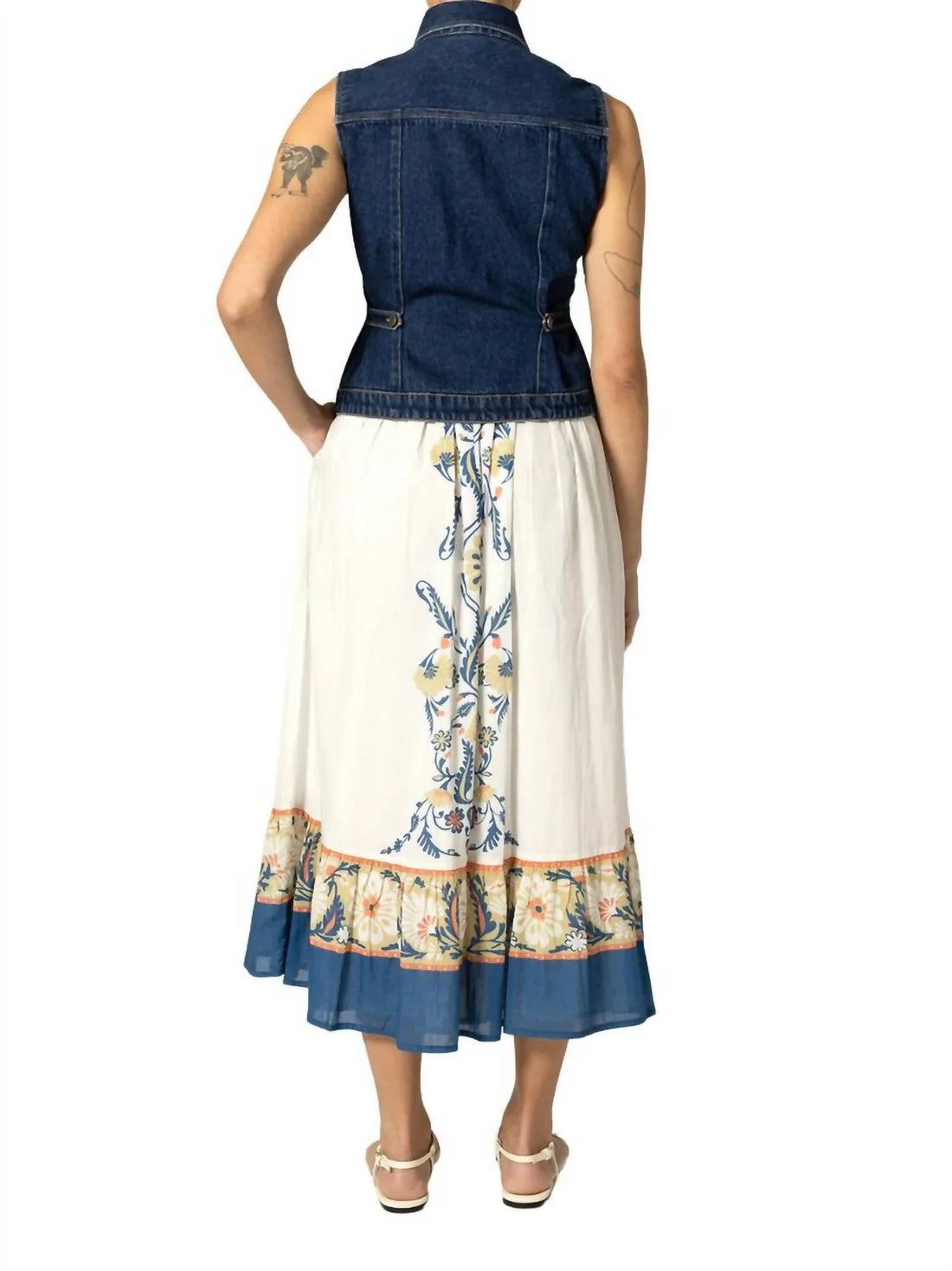 Woman wearing a denim vest over a floral dress on a white background