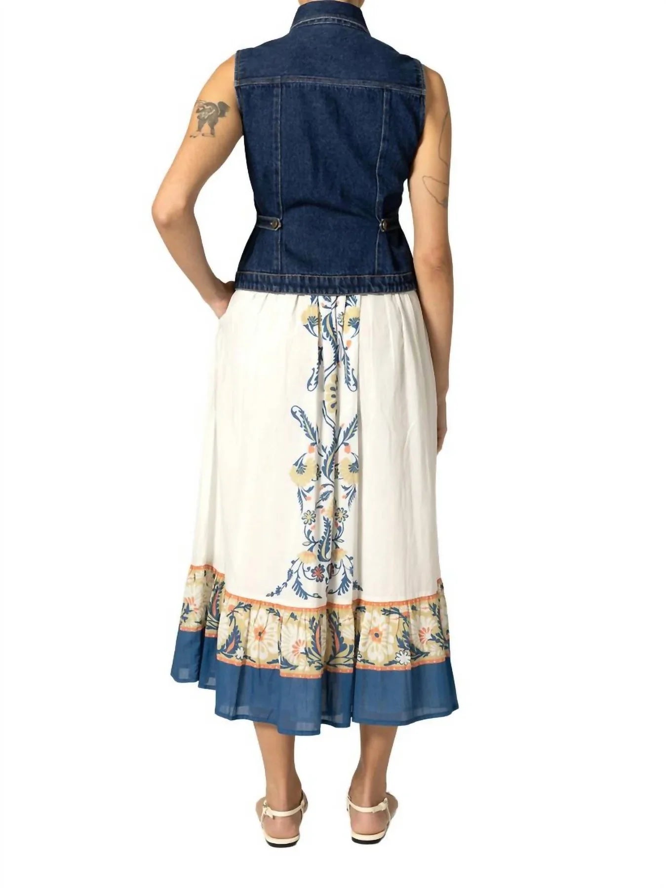 Woman wearing a denim vest over a floral dress on a white background