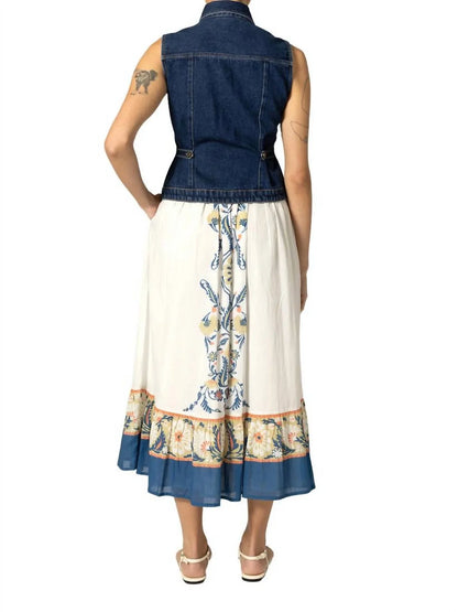 Woman wearing a denim vest over a floral dress on a white background