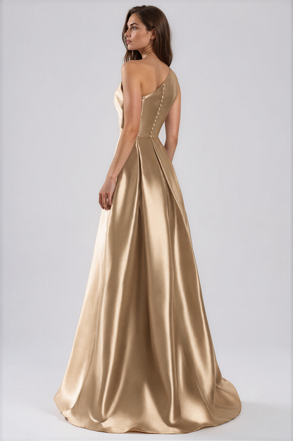 A woman modeling a floor-length satin gown in a warm champagne-gold tone by Daymor One-Shoulder Bow Organza Gown