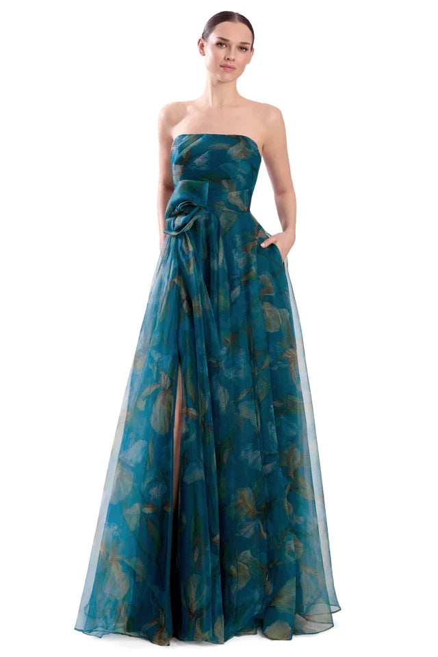 A woman modeling a strapless off-the-shoulder floor-length gown in teal blue-green sheer fabric with a subtle tonal floral pattern. Draped 3D Flower Strapless Gown - Alexander by Daymor 3304F26