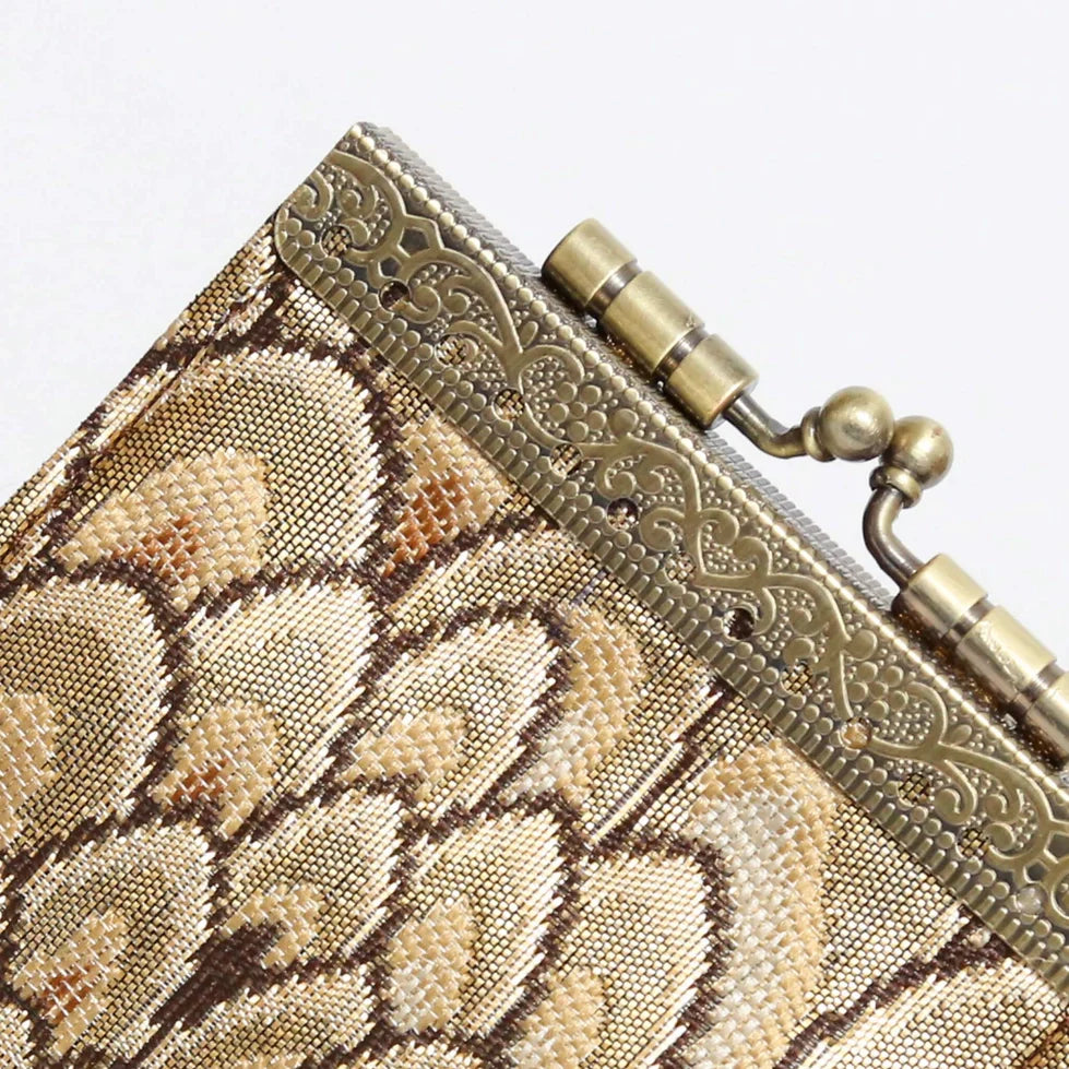 Close-up of a metallic clutch with intricate design and gold accents.