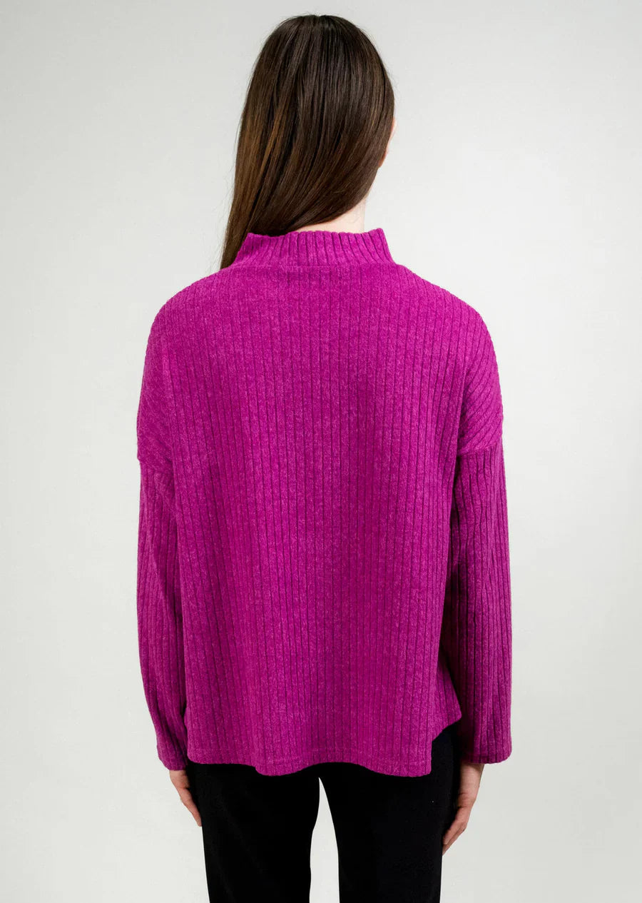Back of a woman wearing a fuchsia sweater against a plain background