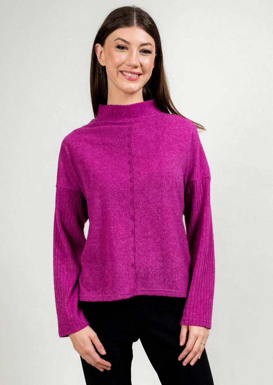 Woman wearing a fuchsia sweater against a plain background