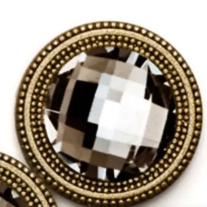 Decorative clothing magnet button with a large crystal center and gold beaded border on a white background