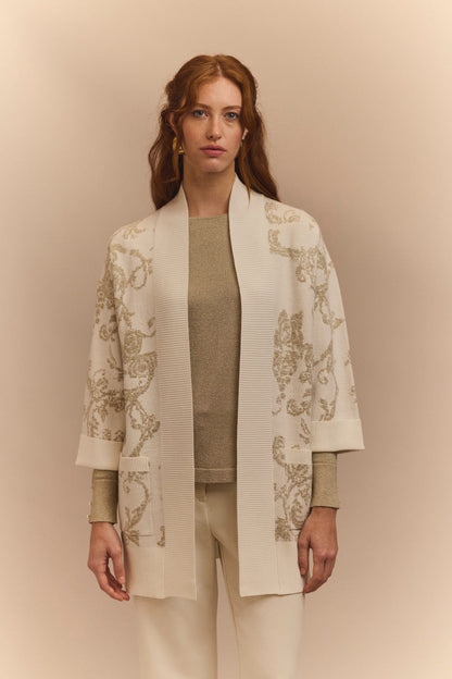 Woman wearing a stylish beige cardigan with floral patterns on a beige background