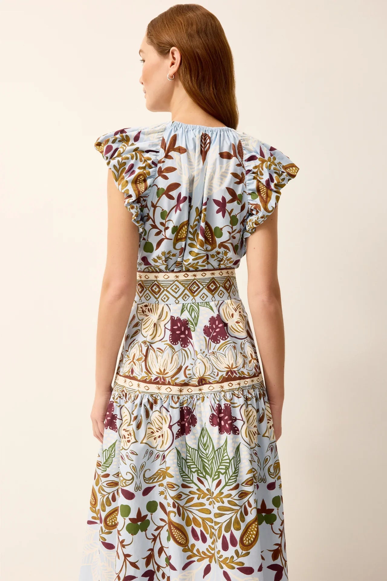 Marie Oliver Leena Dress in lush green fabric with a flowing silhouette, showcased on a mannequin with leafy background.