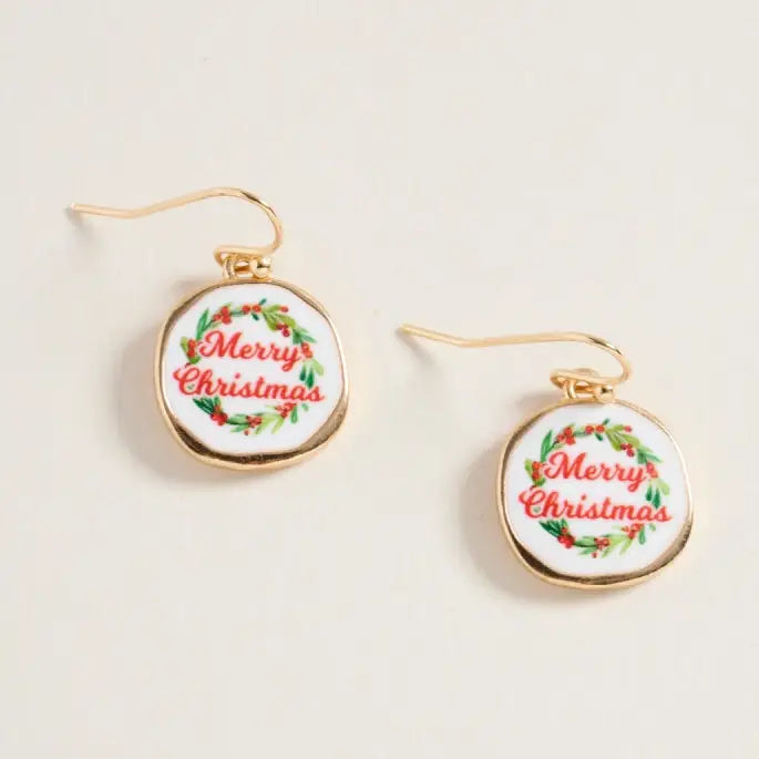 Merry Christmas-themed earrings on a light beige background
