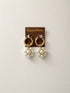 A pair of gold hoop earrings with dangling clusters of white faux pearls in  a flower shape
