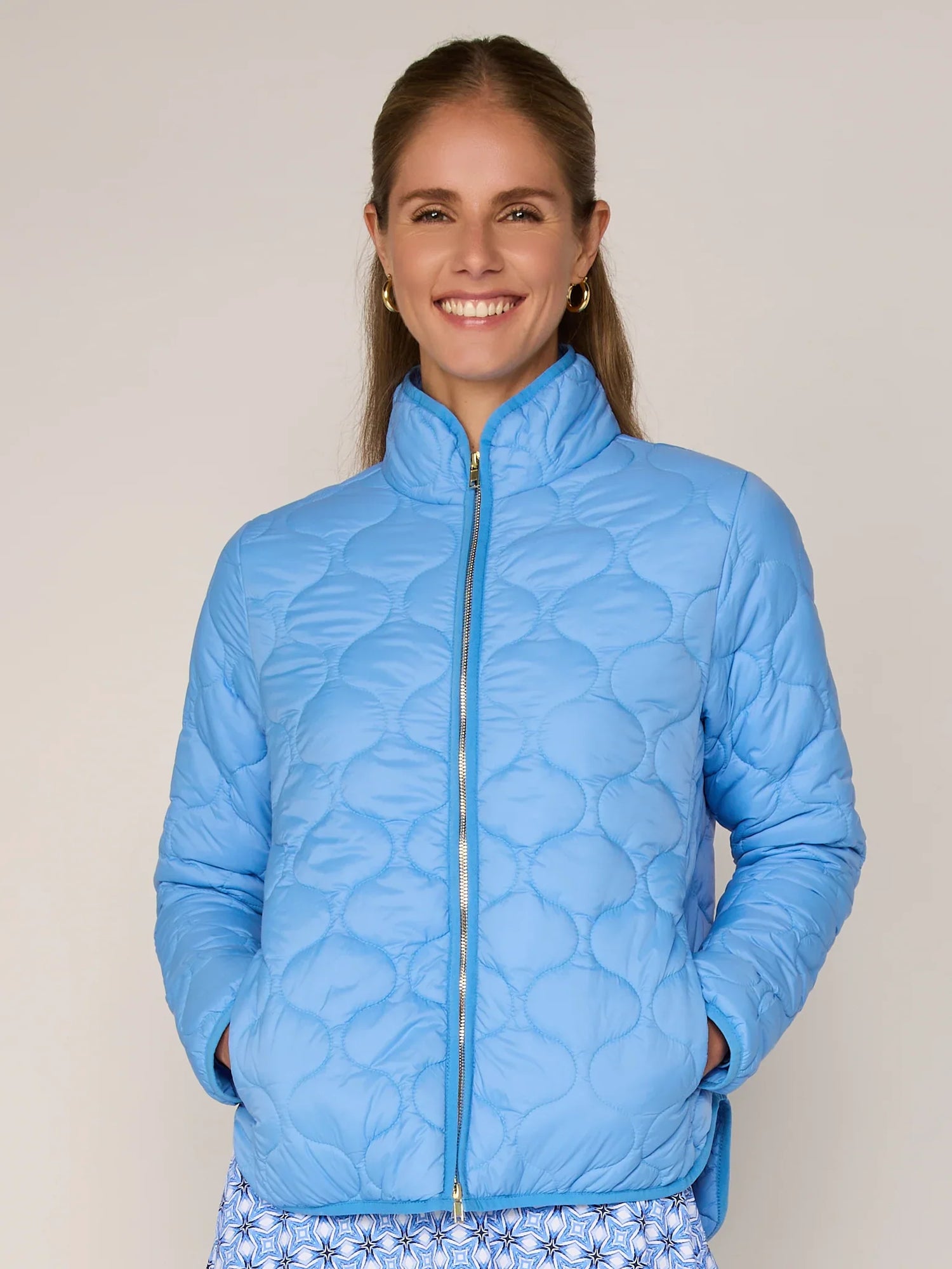 Woman wearing a blue quilted jacket against a plain background