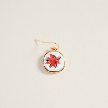 Gold pendant with a red floral design on a beige background
