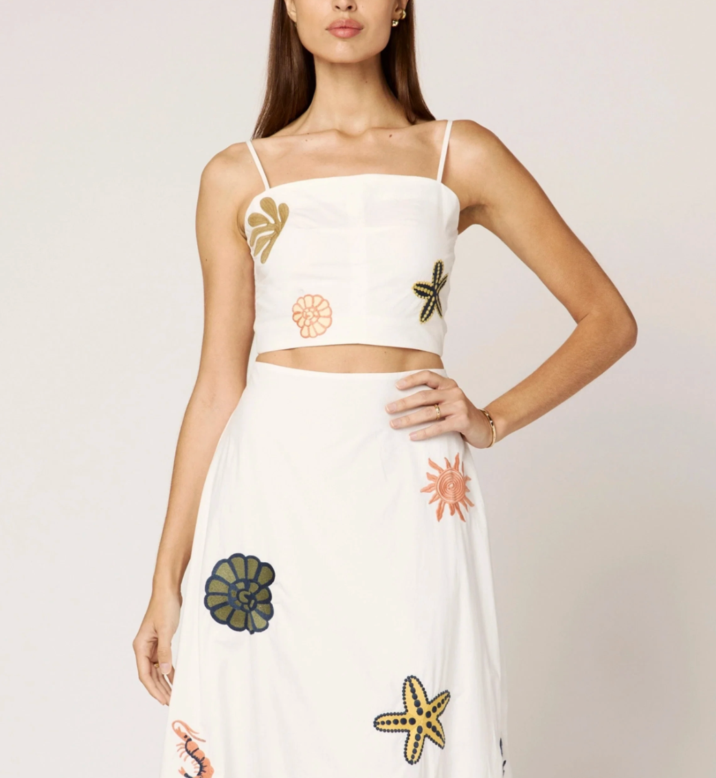 Sage green CLEOBELLA skirt with a fitted waist and flowing fabric, shown on a model in a casual outdoor setting.