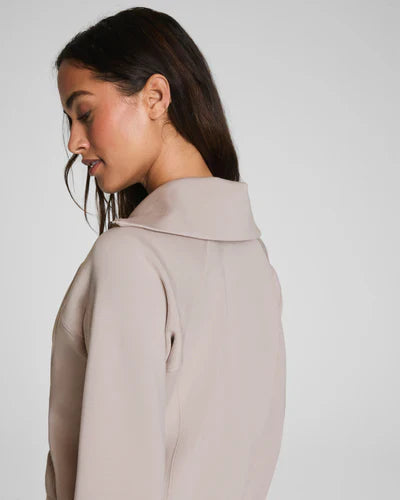 Woman wearing a beige coat against a plain background