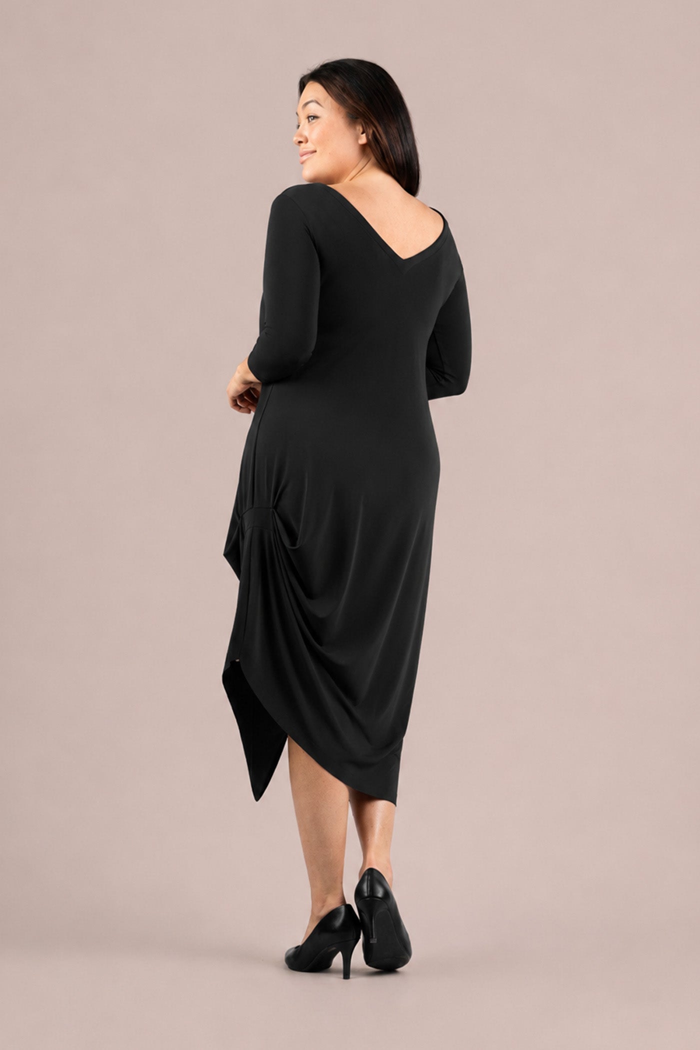 A woman modeling a black three-quarter sleeve midi dress with draped side detail and a high-low hem Sympli Drama Dress 3/4 Sleeves in Black