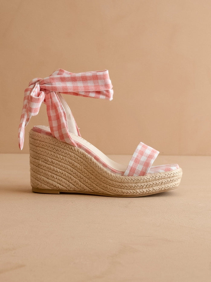 Woven wedge sandal with pink gingham ribbon on a beige background
